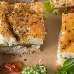 pesto and chicken sandwiches on a board with some pesto