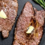 air fryer round steak with pats of butter on top garnished with rosemary