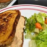 A Simple Tuna Sandwich with a creamy filling is grilled and served on a plate next to a side salad with fresh lettuce and carrots.