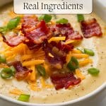 Bowl of creamy Old Fashioned Potato Soup topped with shredded cheddar, crispy bacon pieces, and sliced green onions. Text overlay reads: "Old Fashioned Potato Soup with Real Ingredients.