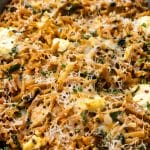 Close-up of a Tuna and Orzo Pasta bake topped with melted cheese, visible herbs, and browned edges.